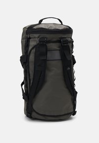 Sac à dos en nylon vert foncé avec des accents noirs, doté de sangles réglables, d'une poignée supérieure et d'une poche en maille à l'avant.