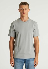 Svijetlosivi kratki rukavi majica izrađena od mekog materijala, s okruglim izrezom i malim izvezenim logotipom na prsima.