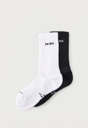 Par de calcetines de caña media con canalé, uno blanco y otro negro, cada uno con el texto "Just do it." en negro o blanco cerca del puño.