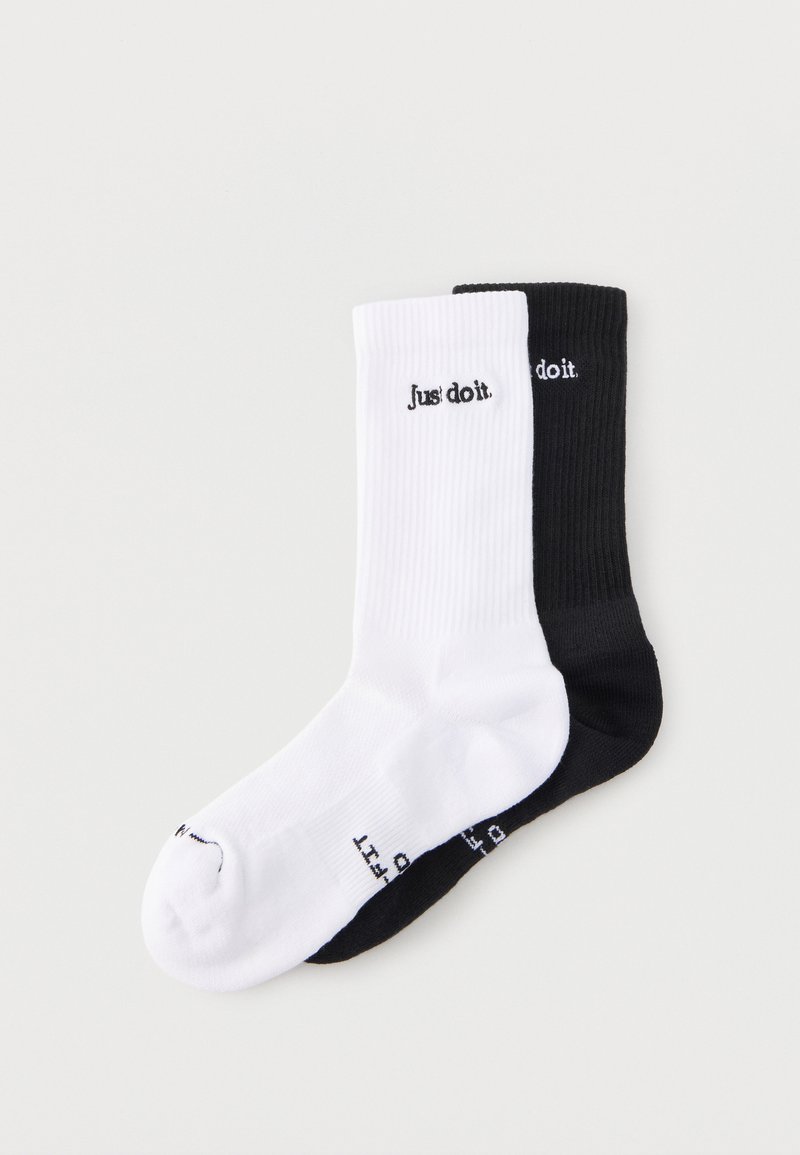 Ζευγάρι ριγωτές κάλτσες για sneaker, μία λευκή και μία μαύρη, η κάθε μία με μαύρο ή λευκό κείμενο "Just do it." κοντά στη μανσέτα.