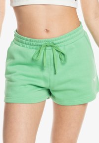 Shorts en mélange de coton vert avec une taille élastique et un cordon de serrage. Présente un petit logo et une texture lisse. Design à mi-cuisse.