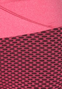 Leggings rosa con una superficie liscia nella parte superiore e una sezione inferiore strutturata e a fantasia con ovali rosa scuro su uno sfondo nero.