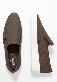 Bottines marron à enfiler avec un motif texturé, des panneaux élastiques sur les côtés et des semelles en caoutchouc blanches. L'intérieur comporte une semelle intérieure avec la marque.
