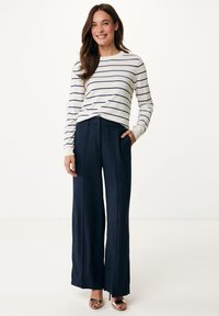 Bílý a námořnický pruhovaný top s dlouhými rukávy v kombinaci s vysokým pasem a širokými námořnickými kalhotami. Tento outfit má uvolněný střih a boční kapsy.