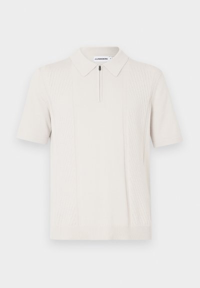 Tricou polo crem cu mâneci scurte, cu guler cu fermoar, având un model în dungi texturate vertical pe ambele părți și tiv striat.