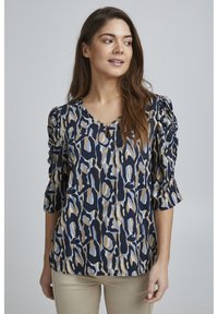 Top a maniche corte con sfondo blu navy e un motivo astratto colorato in blu, beige e sabbia. Tessuto morbido con una vestibilità comoda.