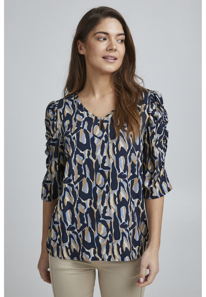 Top a maniche corte con sfondo blu navy e un motivo astratto colorato in blu, beige e sabbia. Tessuto morbido con una vestibilità comoda.