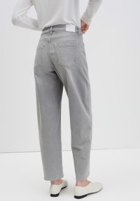 Gray denim trousers with a relaxed fit, five-pocket design, and lightweight texture. The waistband features a plain white label at the back.