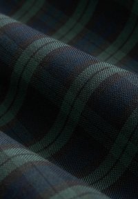 Tessuto tessuto in blu scuro con motivo a quadri verdi. Superficie testurizzata, con strisce alternate e sezioni lisce.
