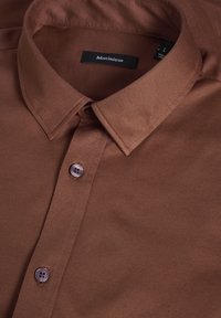 Bruine button-up shirt met een gestructureerde kraag, voorzien van een textuurstof en een knoopsluiting aan de voorkant. Merklabel zichtbaar op de kraag.