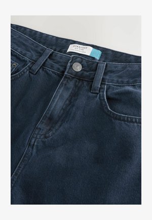 Mørkeblå lige midt-høje jeans med en metalknap og et stykke stoflabel syet ind i linningen.