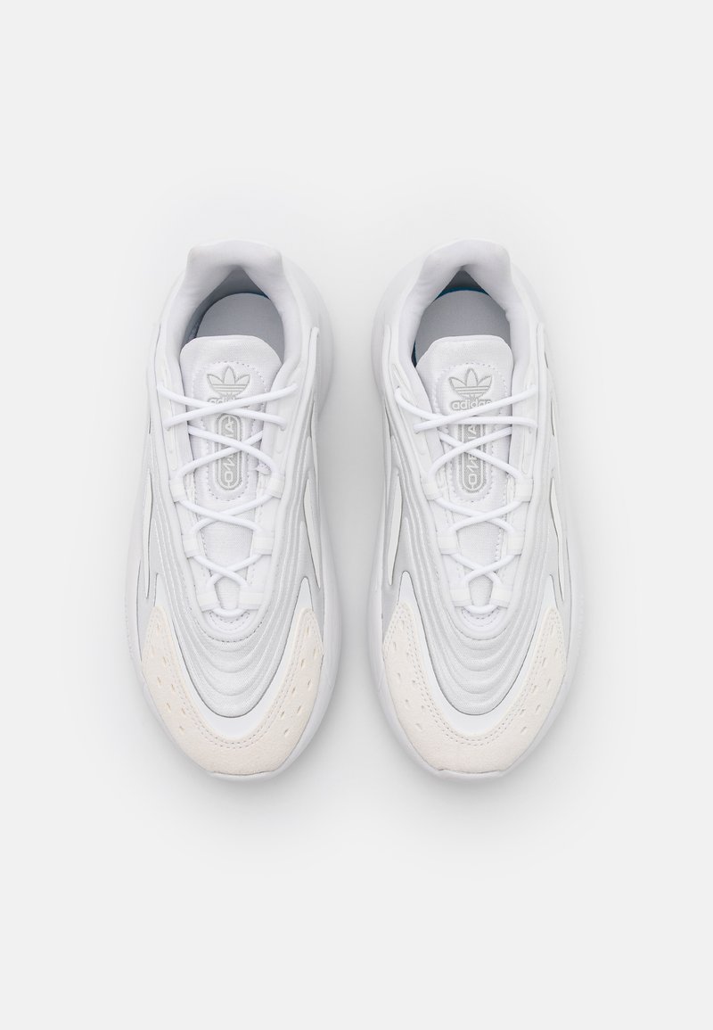 Białe sneakersy z gładką syntetyczną cholewką, teksturowanymi detalami i amortyzującą podeszwą. Wyposażone w sznurowadła oraz minimalistyczny design.