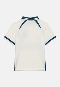 Πόλο κοντομάνικο πουκάμισο με λευκό υφασμάτινο ύφασμα ριπ και λεπτομέρειες σε ναυτικό μπλε στο γιακά και τα μανίκια, παρουσιάζοντας ένα κλασικό σχέδιο.