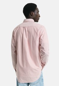 Röd- och vitrandig långärmad skjorta med standardkrage, bakveck, rundad nederkant och knäppta ärmslut. Lättviktig bomullstyg.