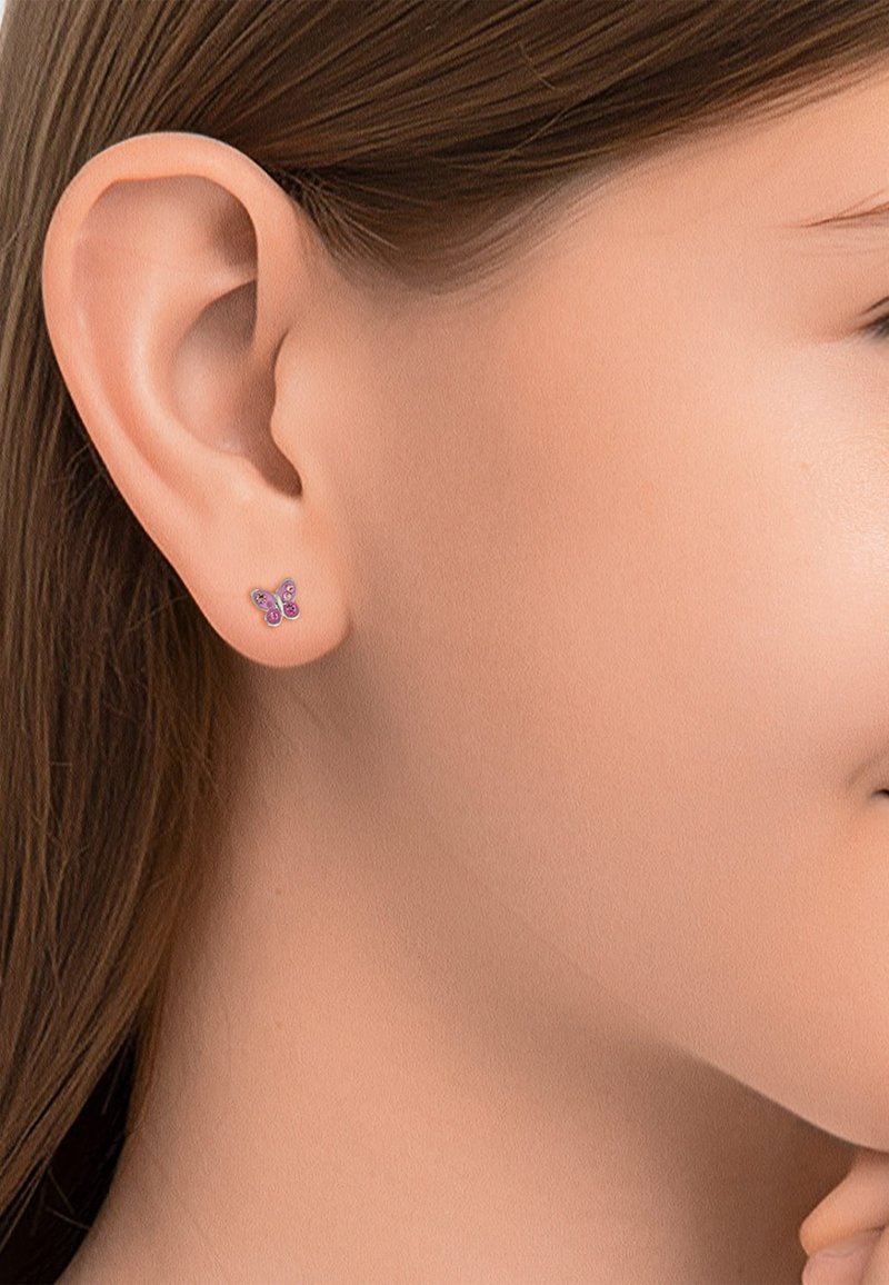Boucle d'oreille en argent en forme de papillon avec des pierres précieuses roses et violettes, présentant une finition brillante et un design délicat des ailes. Portée sur l'oreille d'un modèle.