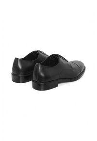 Chaussures habillées en cuir noir avec une finition lisse, bout arrondi et petit talon. Présente un design à lacets et des accents de couture sur le côté.