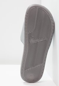 Semelle de sandale Nike grise à slide avec un motif de grip texturé en zigzag et le logo swoosh Nike au centre.