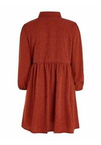 Robe à manches longues couleur rouille avec de petits pois noirs, taille froncée et jupe ample, vue de dos sur fond blanc.