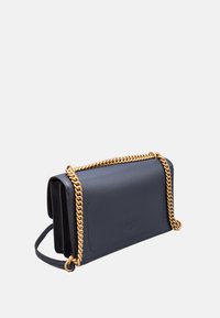 Borsa a tracolla in pelle blu navy con tracolla in catena dorata, forma rettangolare, texture liscia e un logo goffrato discreto sul davanti.