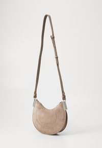 Borsa a tracolla in suede marrone chiaro con forma curvata, tracolla regolabile e dettagli in metallo argentato. Presenta una chiusura con zip e dettagli di cucitura.