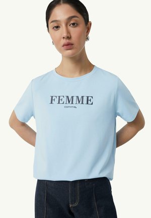 Lichtblauw t-shirt met korte mouwen en ronde halslijn, met centraal in witte letters "FEMME" gedrukt. Zachte, gladde stof; ontspannen pasvorm.