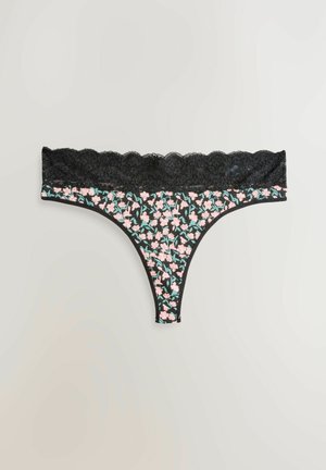 Schwarzer Tanga mit Spitzenbesatz, verziert mit einem floralen Muster in Pink und Grün auf dunklem Hintergrund, aus glattem Stoff und mit gewelltem Rand.