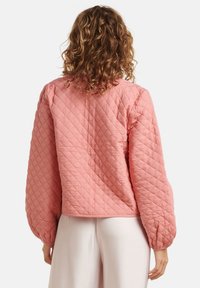 Gepolsterde roze jas met een cropped ontwerp, ballonmouwen en een gladde textuur, voorzien van een eenvoudige kraag en zonder zichtbare hardware.