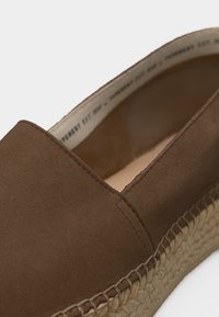 Καφέ εσπαντρίγια από σουέτ με πλεκτή σόλα από τζουτ και ορατή ραφή κατά μήκος του επάνω άκρου.