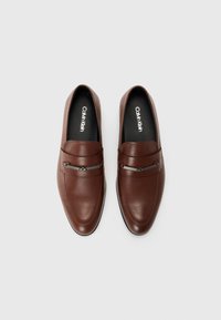 Brown leather loafers with sleek design, contrast stitching, and a silver-tone accent across the upper. Black insole with logo.