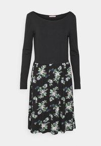 Long-sleeve dress with a black top and a flared floral skirt featuring white and green flowers on a black background. Smooth fabric texture.