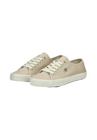 Sneaker in tela beige con lacci bianchi, punta rotonda e suola in gomma. Presenta un piccolo logo sul lato e un tessuto testurizzato.