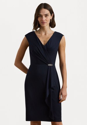 Donkerblauwe mouwloze jurk met een V-hals, wikkelontwerp, gedrapeerd stof en een zilverkleurige metalen accent bij de taille. Soepele textuur.
