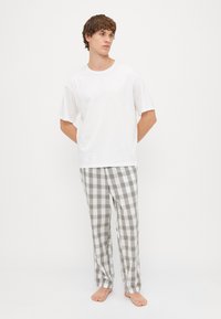 Vit bomull t-shirt med korta ärmar, tillsammans med randiga pyjamasbyxor i grå, vit och grön nyanser, med en avslappnad passform och raka ben.