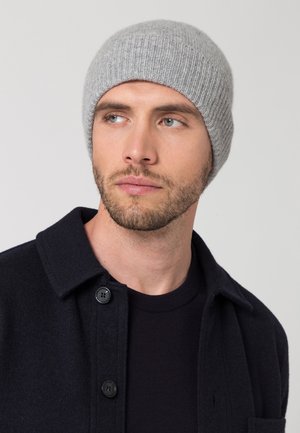 Gray ribbed knit beanie, soft wool material, close-fitting design, worn with a dark jacket featuring black buttons and a round neck.