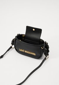 Black faux leather crossbody bag with gold "LOVE MOSCHINO" lettering, braided side handle accents, and a snap-button wallet inside.