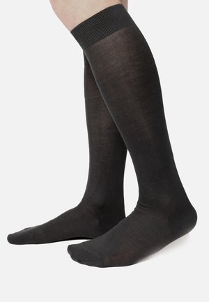 Calze nere fino al ginocchio realizzate in un materiale liscio e elasticizzato, con un bordo superiore rigato e un design aderente che si adatta alla gamba.