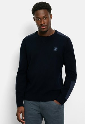 Navy knit sweater with long sleeves, textured fabric, and shoulder patches in a darker shade. Features a small logo on the chest.