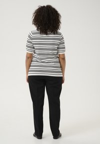 Pulover cu dungi alb-negru, cu mâneci scurte, asortat cu pantaloni negri. Textură fină, design ajustat, vedere din spate, stil simplu și clasic.