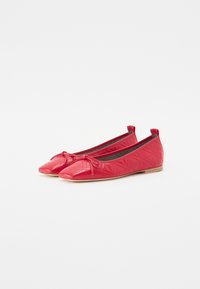 Ballerines matelassées rouges avec un bout pointu, détail de nœud à l'avant et semelle plate basse. Présentent une texture lisse et brillante.