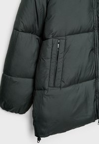 Giacca a vento nera con design trapuntato, dotata di tasca con zip, orlo elastico e superficie liscia e lucida. Versatile e isolante.