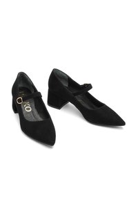 Black suede Mary Jane heels with pointed toes, a mid-height block heel, and a thin strap across the foot featuring a gold-colored buckle.