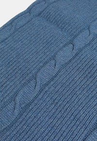 Tessuto blu lavorato a maglia con un design a coste e un motivo centrale a treccia. Il materiale ha una consistenza morbida e una trama uniforme.