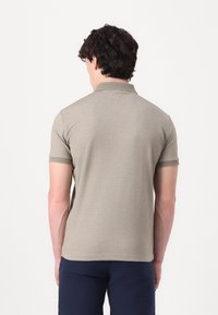 Polo en beige clair avec une finition texturée, doté d'un col et de manches courtes, associé à un short marine.