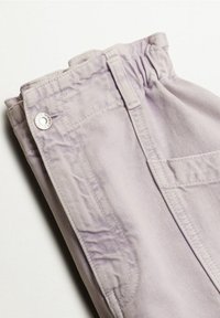 Pantalon violet clair plié avec une ceinture élastique, des coutures visibles, des passants de ceinture et une fermeture à bouton métallique sur fond blanc.