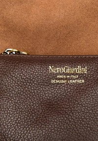 Portafoglio marrone in pelle genuina con superficie testurizzata. Presenta testo in rilievo dorato: "NeroGiardini MADE IN ITALY PELLE GENUINA." Chiusura sicura con zip.