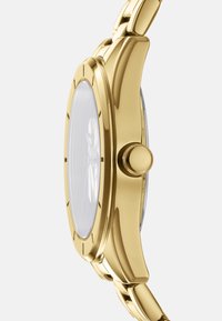 Orologio in metallo dorato con cassa rotonda, superficie liscia e quadrante di vetro trasparente. Ha un pulsante laterale e un bracciale a maglie.