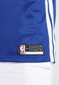 Canotta NBA blu e bianca con etichetta "Swingman", taglia 44 e logo Nike sull'orlo inferiore.