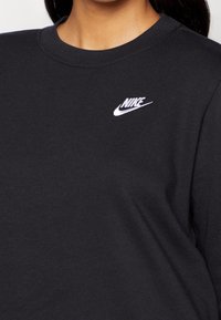 Czarna bluza z okrągłym dekoltem, wykonana z miękkiego materiału. Posiada małe białe logo Nike na lewej części klatki piersiowej.