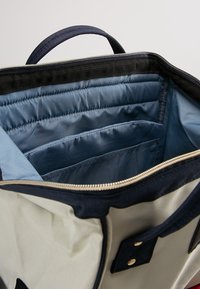 Wnętrze torby płóciennej z wyściełanymi kieszeniami w ciemnoniebieskim i jasnoniebieskim kolorze. Posiada zamek błyskawiczny oraz granatowy uchwyt. Teksturowane czarne wykończenie.