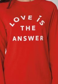 Sweat-shirt en coton rouge avec un col rond, arborant un texte blanc qui dit "LOVE IS THE ANSWER" avec un petit cœur au-dessus du mot "is".
